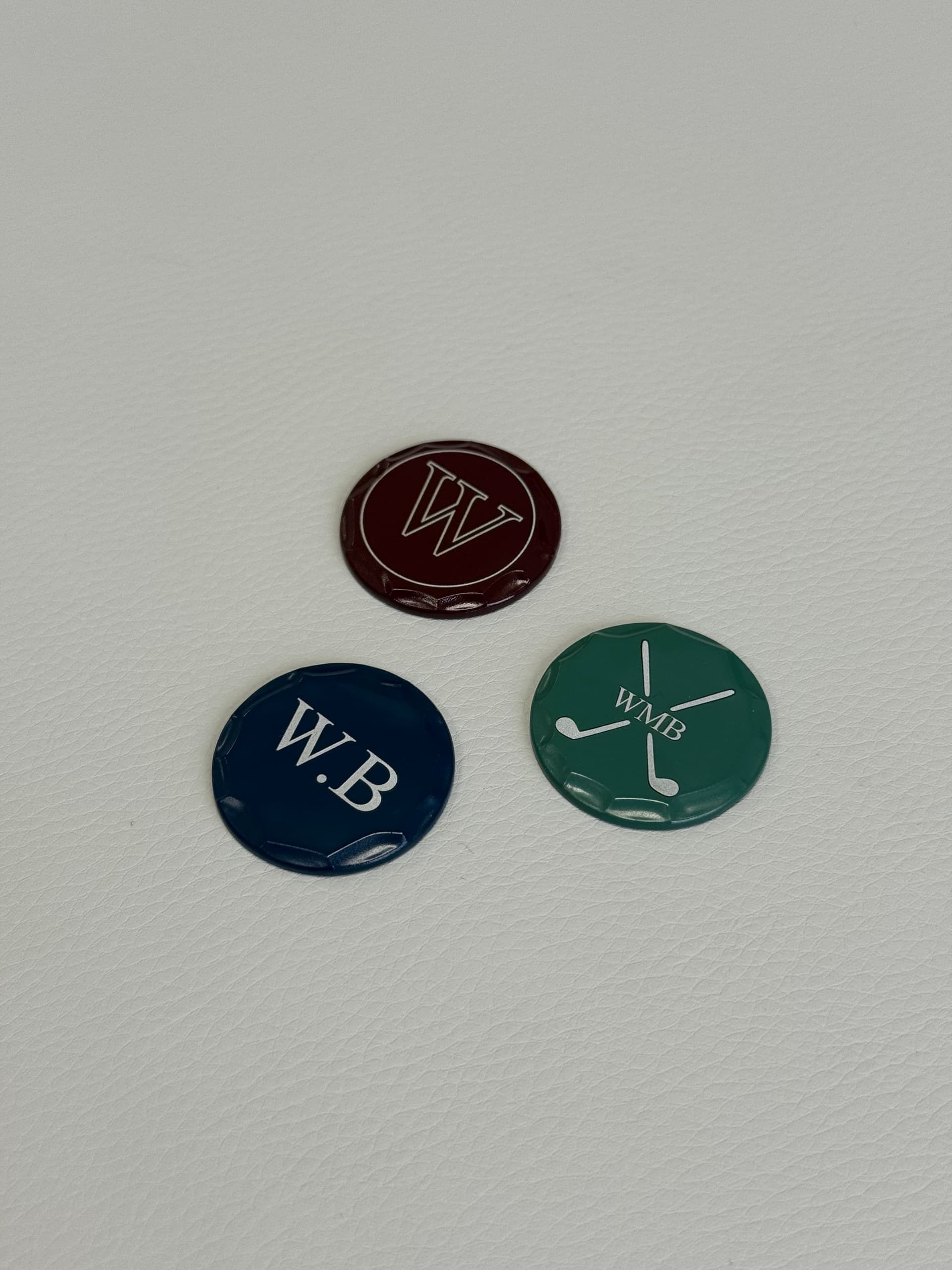 Personalised golf ball markers in green, burgundy and navy with engraved initials